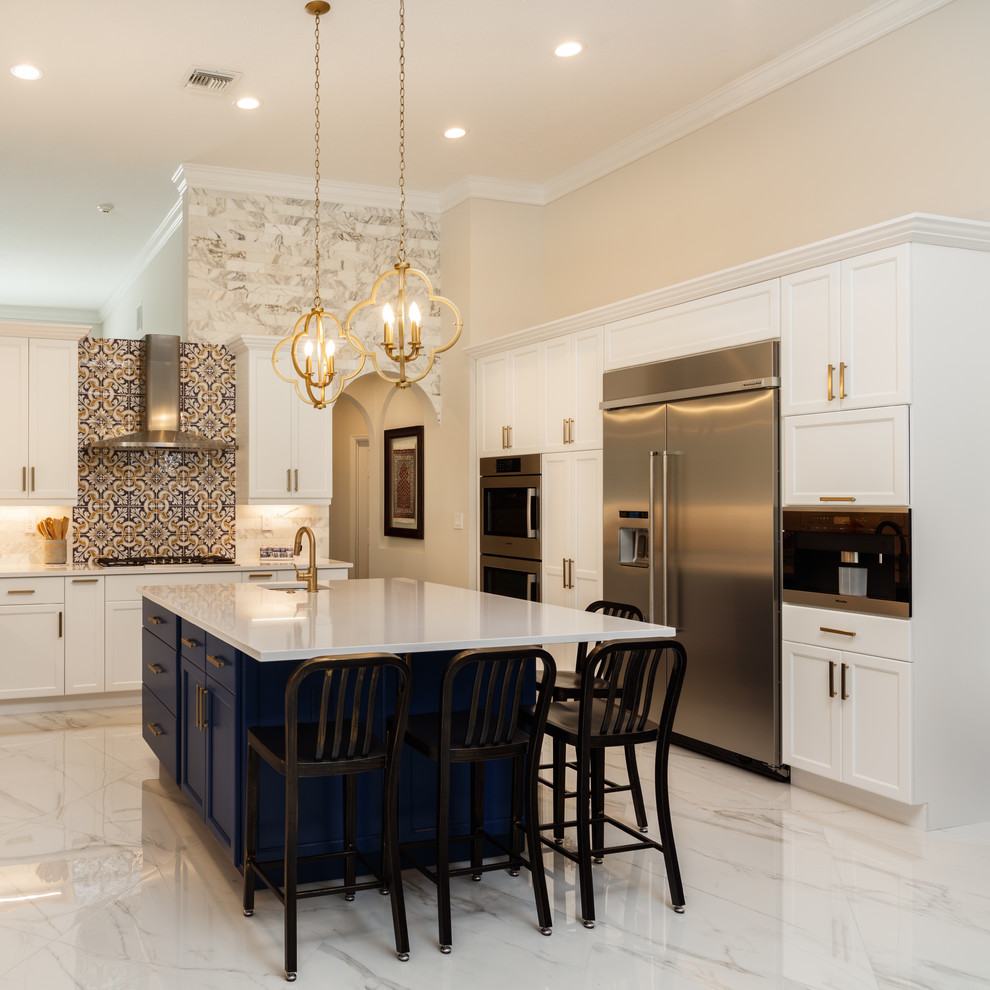 This is an example of a large classic u-shaped open plan kitchen in Miami with a submerged sink, recessed-panel cabinets, white cabinets, engineered stone countertops, white splashback, porcelain splashback, stainless steel appliances, porcelain flooring, an island, white floors and white worktops.