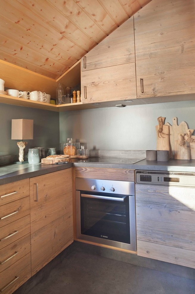 Inredning av ett rustikt litet grå grått kök, med en enkel diskho, skåp i ljust trä, bänkskiva i betong, grått stänkskydd, rostfria vitvaror, betonggolv och grått golv