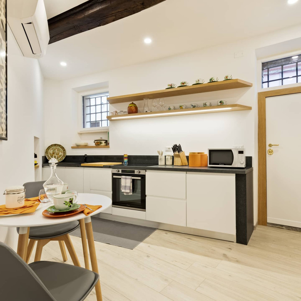 Idéer för att renovera ett litet funkis grå linjärt grått kök och matrum, med en enkel diskho, släta luckor, vita skåp, granitbänkskiva, grått stänkskydd, rostfria vitvaror, klinkergolv i porslin och beiget golv