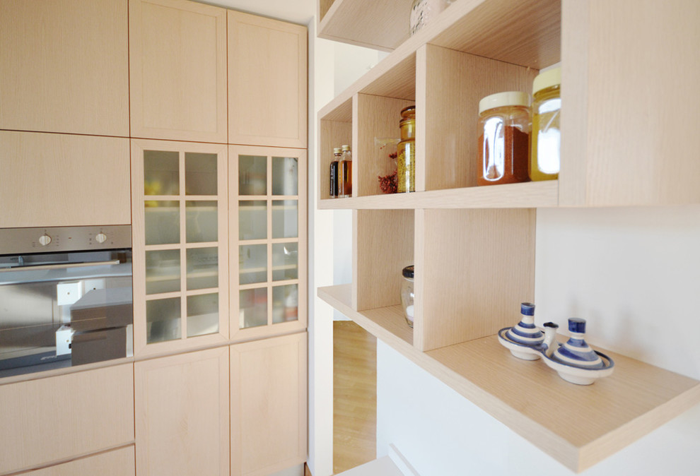 На фото: кухня среднего размера в современном стиле с светлыми деревянными фасадами и полуостровом с