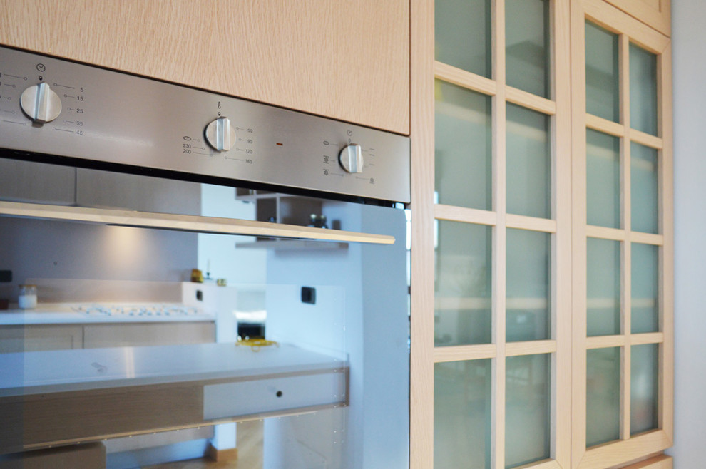 Foto di una cucina design di medie dimensioni con ante in legno chiaro e penisola