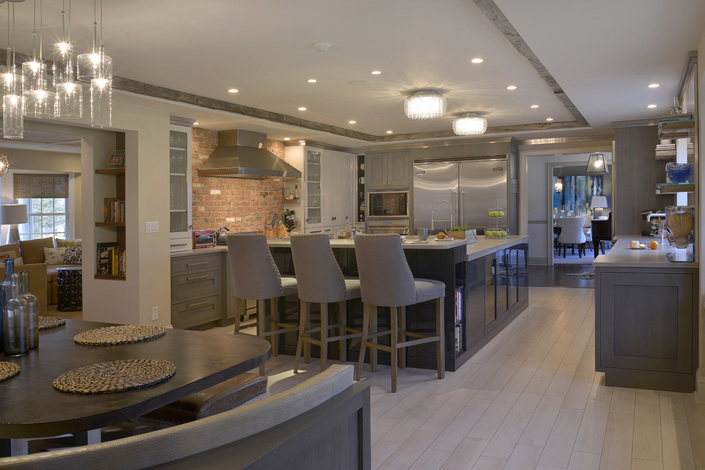 Example of a large minimalist u-shaped light wood floor eat-in kitchen design in New York with a farmhouse sink, glass-front cabinets, gray cabinets, granite countertops, stainless steel appliances and two islands