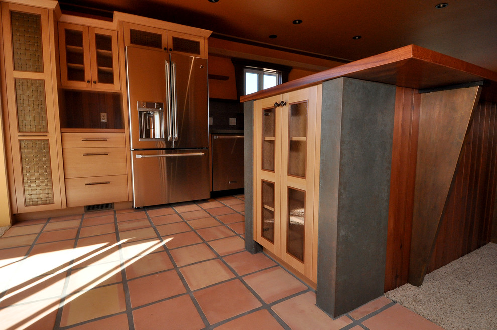 Exempel på ett mellanstort maritimt kök, med en undermonterad diskho, skåp i shakerstil, skåp i ljust trä, bänkskiva i betong, stänkskydd med metallisk yta, stänkskydd i porslinskakel, rostfria vitvaror, klinkergolv i terrakotta, en halv köksö och rött golv