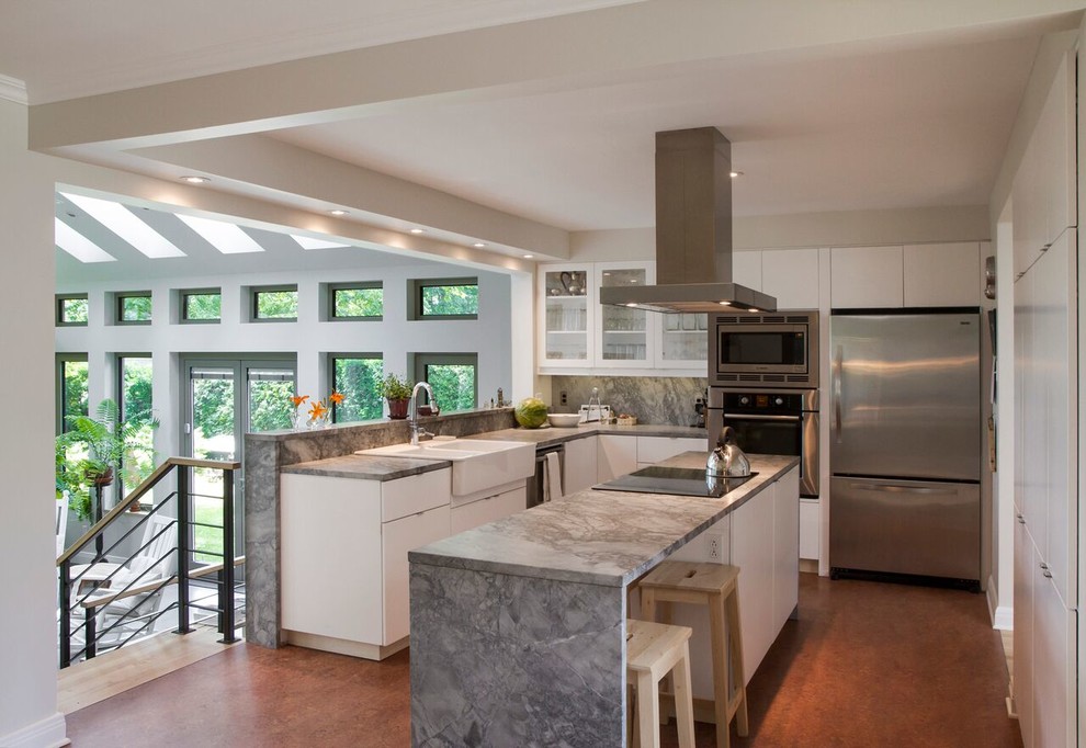 Example of a mid-sized transitional l-shaped linoleum floor and brown floor open concept kitchen design in Montreal with flat-panel cabinets, white cabinets, granite countertops, gray backsplash, stone slab backsplash, an island, a farmhouse sink and stainless steel appliances