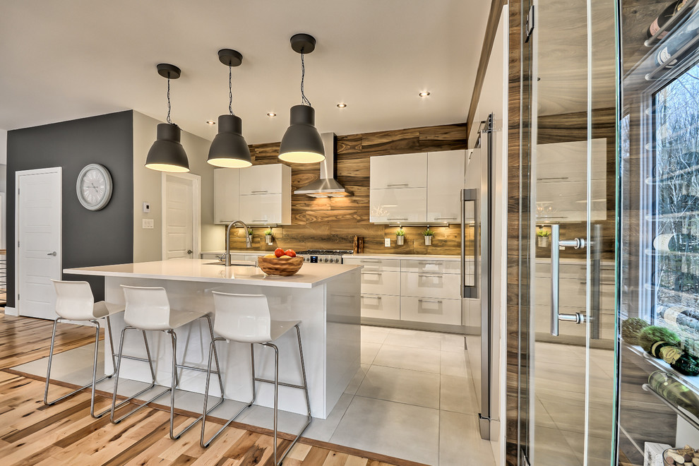 Mid-sized trendy l-shaped porcelain tile and white floor eat-in kitchen photo in Montreal with an undermount sink, flat-panel cabinets, white cabinets, solid surface countertops, porcelain backsplash, stainless steel appliances and an island