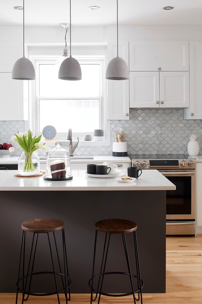 Exempel på ett modernt kök, med en undermonterad diskho, vita skåp, bänkskiva i kvarts, grått stänkskydd, stänkskydd i stenkakel, rostfria vitvaror, ljust trägolv och en köksö