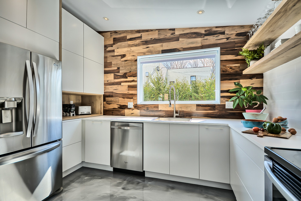 Bild på ett mellanstort funkis kök, med en dubbel diskho, släta luckor, vita skåp, laminatbänkskiva, vitt stänkskydd, stänkskydd i keramik, rostfria vitvaror, betonggolv och grått golv