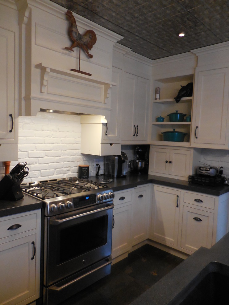 Bild på ett avskilt, litet amerikanskt l-kök, med en undermonterad diskho, luckor med profilerade fronter, vita skåp, bänkskiva i betong, vitt stänkskydd, stänkskydd i tegel, rostfria vitvaror, skiffergolv och en köksö