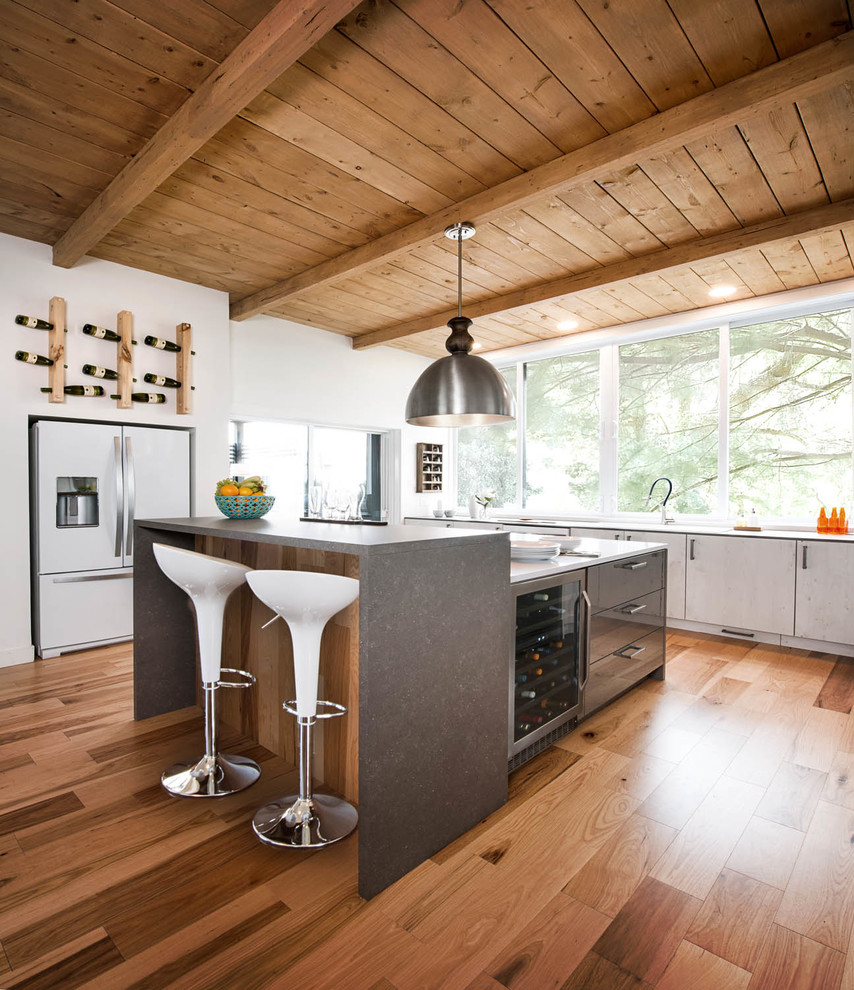Open concept kitchen - mid-sized contemporary l-shaped light wood floor open concept kitchen idea in Montreal with a farmhouse sink, flat-panel cabinets, white cabinets, white appliances and an island