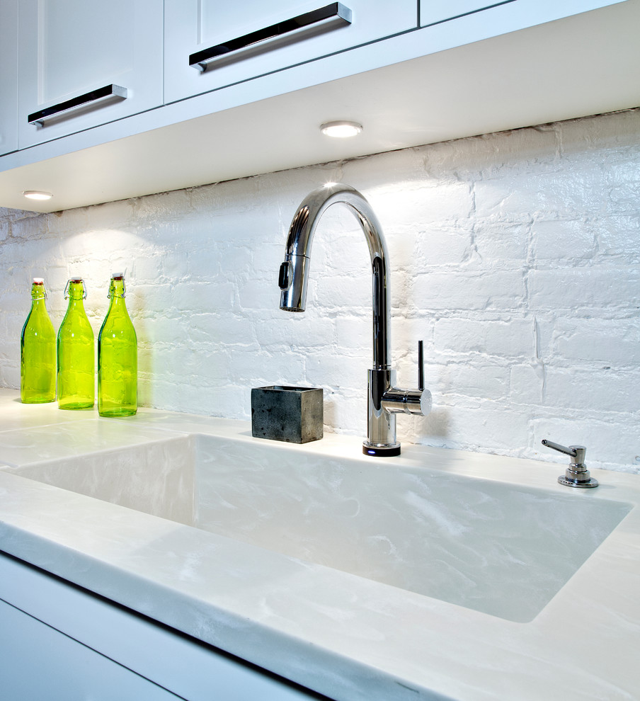 Imagen de cocina comedor contemporánea con puertas de armario blancas, salpicadero blanco, electrodomésticos de acero inoxidable, suelo de baldosas de porcelana y una isla