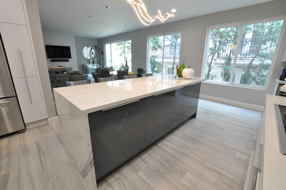 Bild på ett stort funkis kök och matrum, med släta luckor, vita skåp, granitbänkskiva, vitt stänkskydd, stänkskydd i sten, rostfria vitvaror, ljust trägolv och en köksö