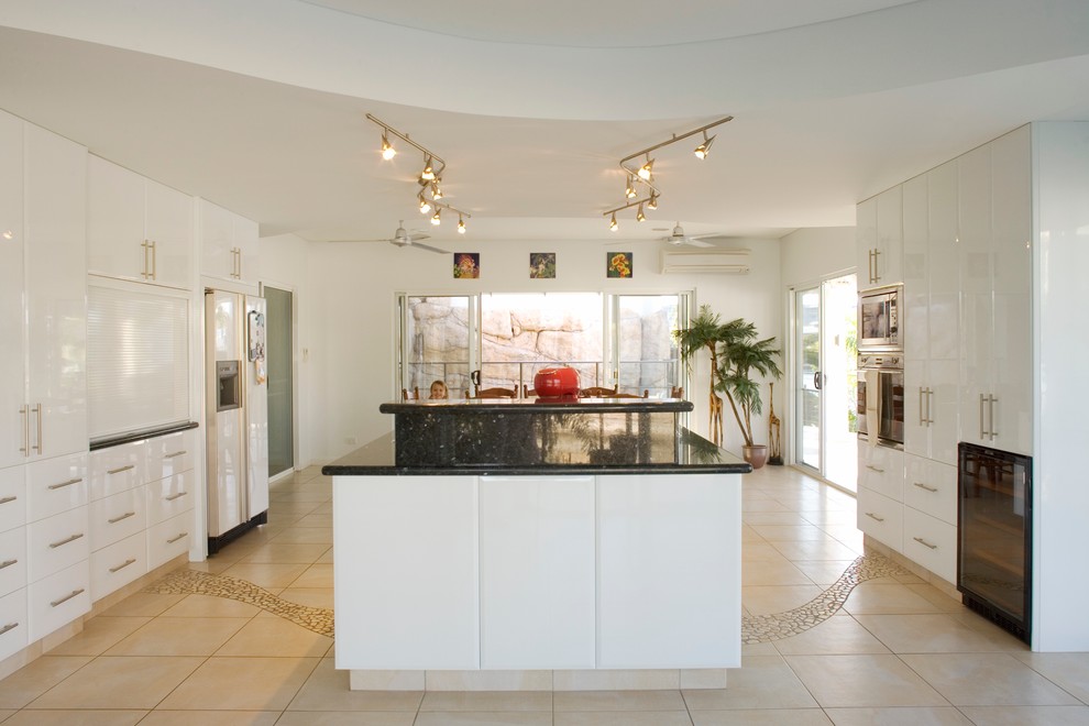 Immagine di una cucina tropicale di medie dimensioni con ante lisce, ante bianche, top in granito, elettrodomestici in acciaio inossidabile e pavimento con piastrelle in ceramica
