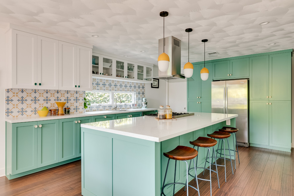 Photo of a medium sized nautical single-wall kitchen in Los Angeles with a single-bowl sink, shaker cabinets, green cabinets, engineered stone countertops, multi-coloured splashback, porcelain splashback, stainless steel appliances, medium hardwood flooring, an island, brown floors and white worktops.