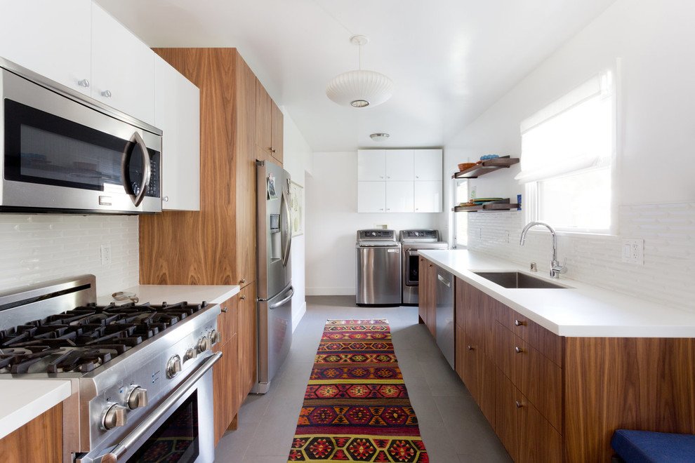 Moderne Küche ohne Insel mit Unterbauwaschbecken, flächenbündigen Schrankfronten, hellbraunen Holzschränken, Küchenrückwand in Weiß und Küchengeräten aus Edelstahl in Los Angeles