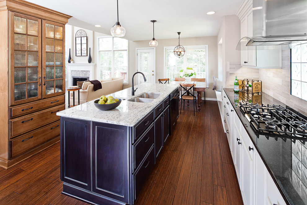 Mid-sized cottage galley medium tone wood floor and brown floor eat-in kitchen photo in Charlotte with an undermount sink, recessed-panel cabinets, granite countertops, limestone backsplash, stainless steel appliances, an island, multicolored countertops and beige backsplash