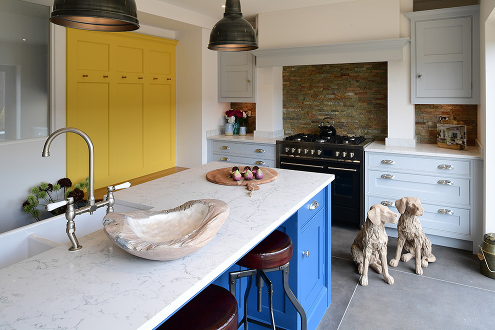 Inspiration for a medium sized contemporary kitchen in London with porcelain flooring, grey floors, a double-bowl sink, recessed-panel cabinets, blue cabinets, brown splashback, brick splashback, black appliances, an island and white worktops.