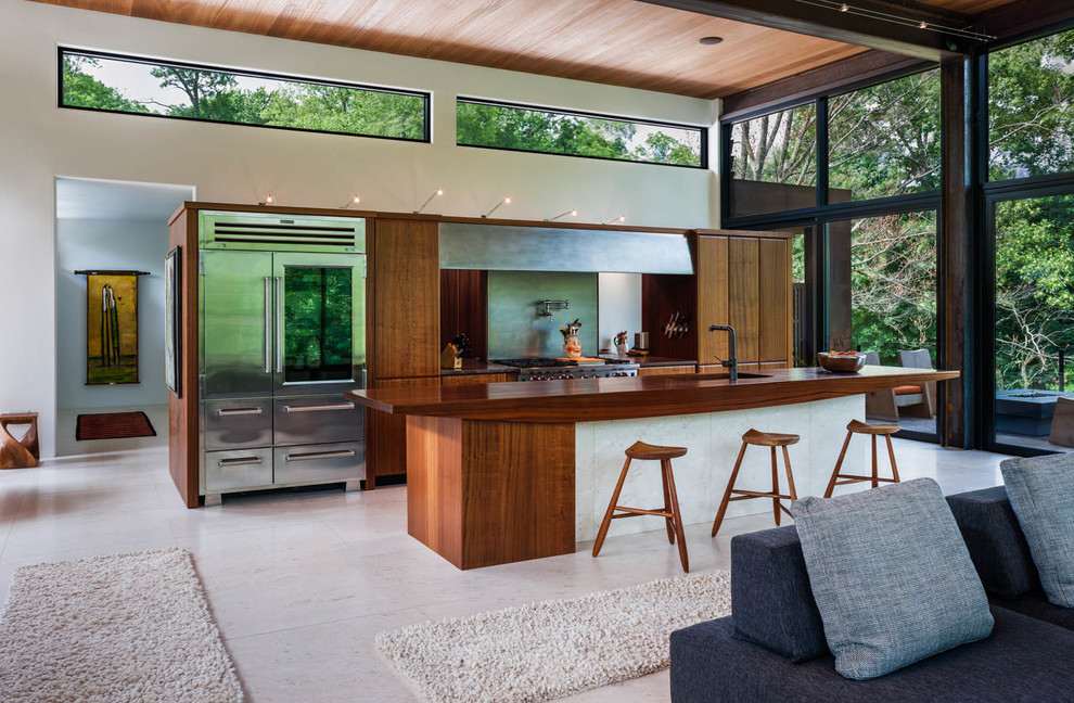Exemple d'une grande cuisine ouverte linéaire tendance en bois brun avec un placard à porte plane, un électroménager en acier inoxydable, îlot, un évier encastré et un plan de travail en bois.