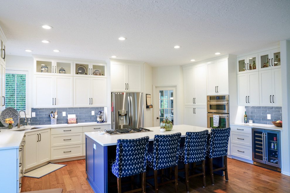 Mid-sized transitional u-shaped medium tone wood floor and brown floor eat-in kitchen photo in Portland with an undermount sink, shaker cabinets, white cabinets, quartzite countertops, blue backsplash, porcelain backsplash, stainless steel appliances, an island and white countertops