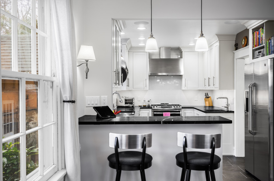 Small modern u-shaped enclosed kitchen in San Diego with a submerged sink, shaker cabinets, white cabinets, soapstone worktops, white splashback, ceramic splashback, stainless steel appliances, porcelain flooring, a breakfast bar, grey floors and black worktops.