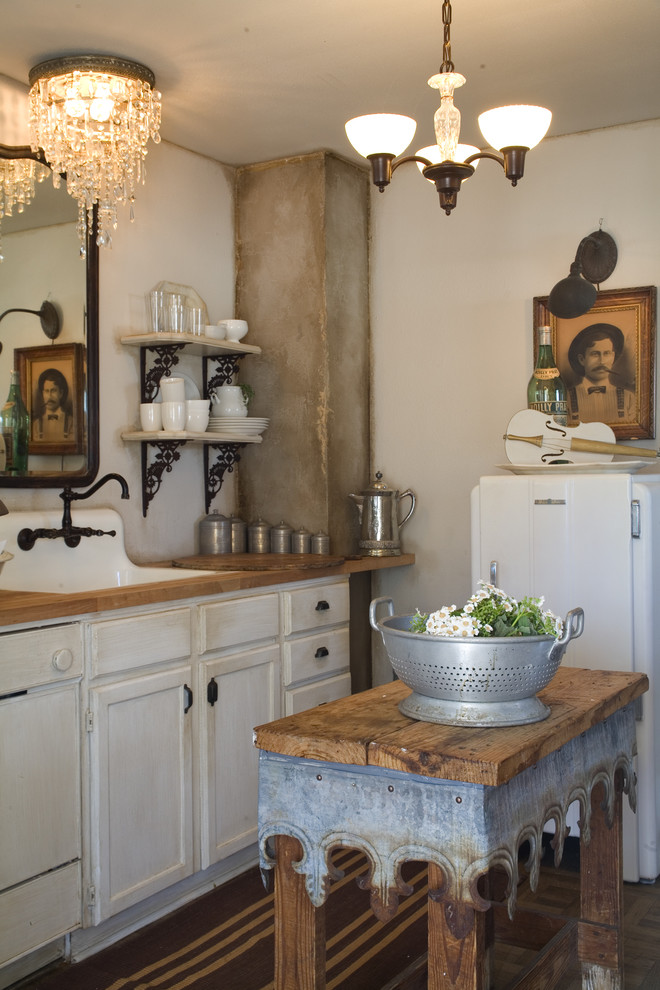 Example of a cottage chic kitchen design in Other with wood countertops, white cabinets, white appliances and a farmhouse sink