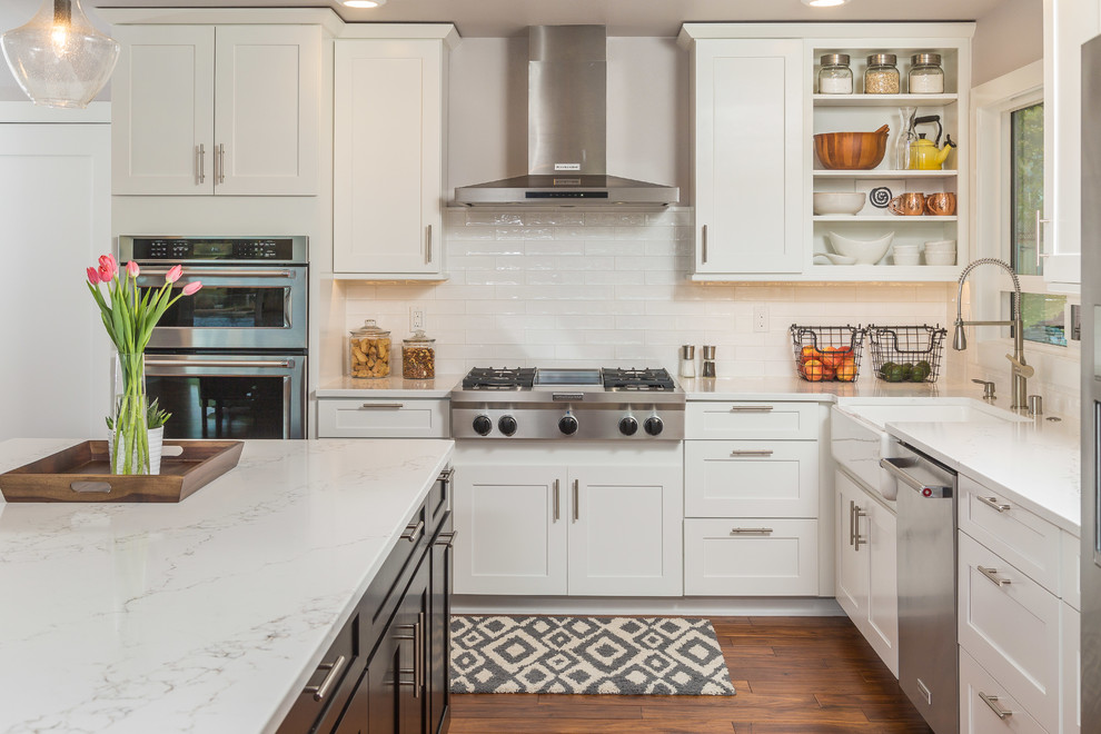 Klassische Küche in L-Form mit Landhausspüle, Schrankfronten im Shaker-Stil, weißen Schränken, Küchenrückwand in Weiß, Küchengeräten aus Edelstahl und Kücheninsel in Sonstige
