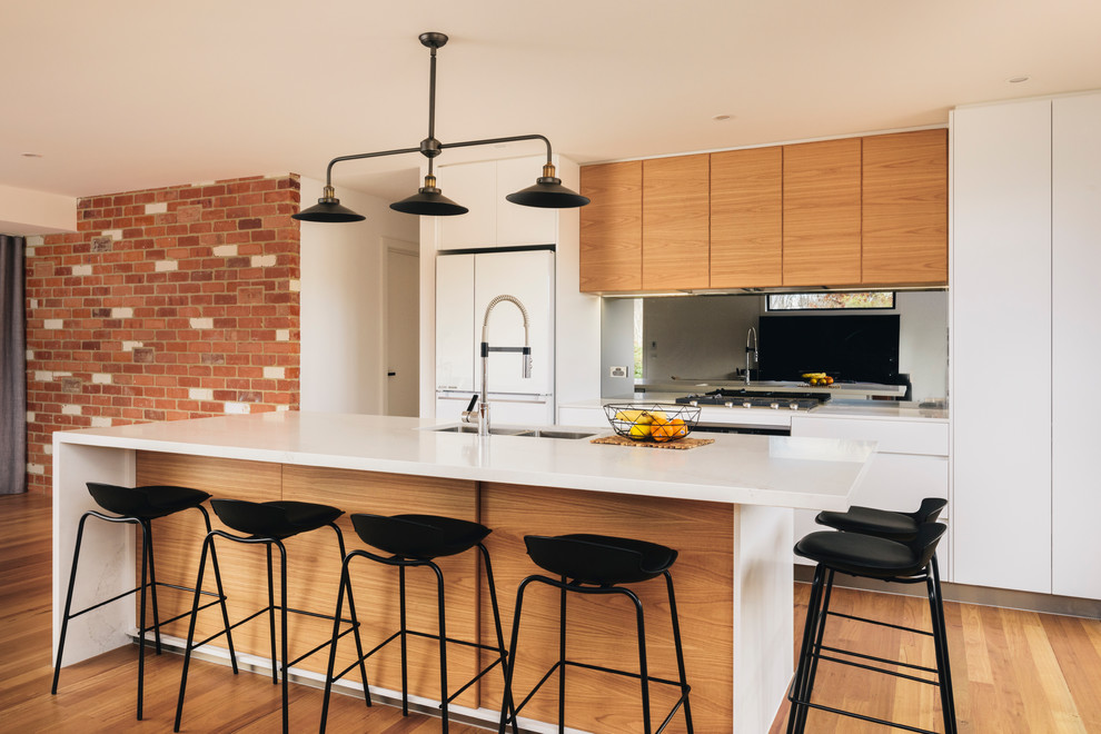 Moderne Küche mit hellbraunen Holzschränken, Marmor-Arbeitsplatte, Rückwand aus Spiegelfliesen, braunem Holzboden und Kücheninsel in Canberra - Queanbeyan