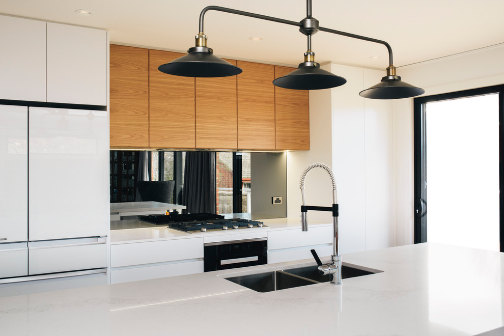 Aménagement d'une cuisine parallèle industrielle avec un évier encastré, plan de travail en marbre, une crédence miroir, un sol en bois brun et îlot.