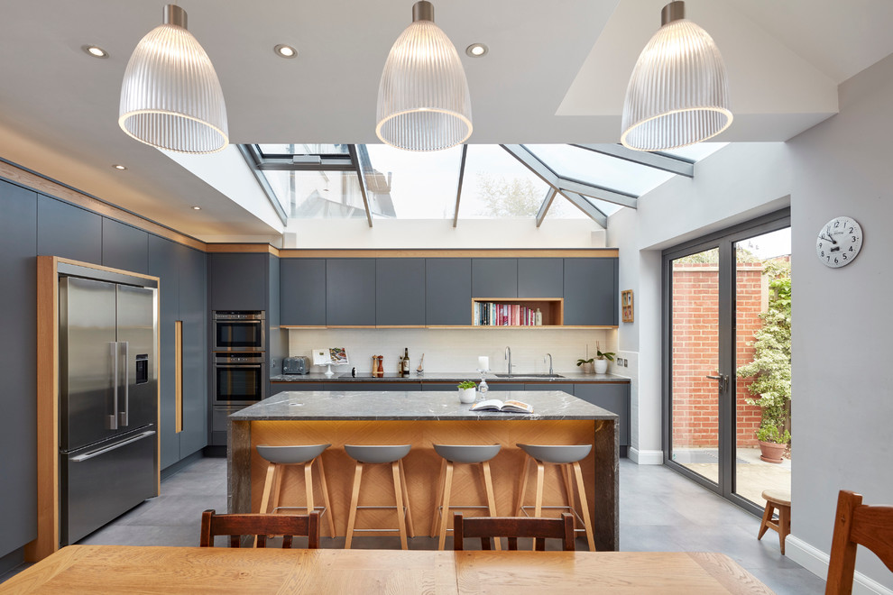 Große Moderne Wohnküche in L-Form mit Unterbauwaschbecken, flächenbündigen Schrankfronten, grauen Schränken, Küchenrückwand in Weiß und Kücheninsel in London