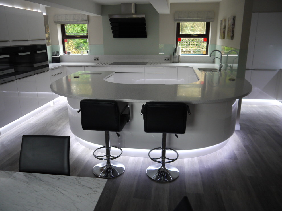 Стильный дизайн: п-образная кухня среднего размера в современном стиле с обеденным столом, плоскими фасадами, белыми фасадами, фартуком из стекла и полуостровом - последний тренд