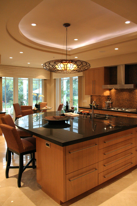 Inredning av ett modernt kök, med en undermonterad diskho, släta luckor, skåp i mellenmörkt trä, granitbänkskiva, brunt stänkskydd, rostfria vitvaror, travertin golv och en köksö