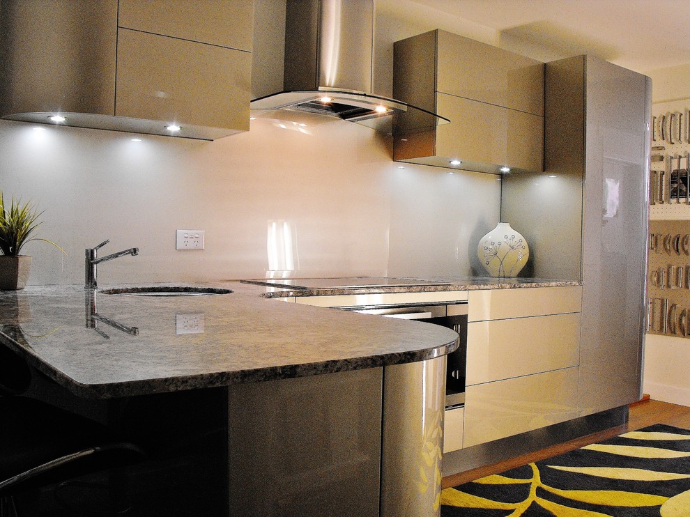 Modern inredning av ett mellanstort kök, med en enkel diskho, luckor med glaspanel, granitbänkskiva, rostfria vitvaror, bambugolv, stänkskydd med metallisk yta och glaspanel som stänkskydd