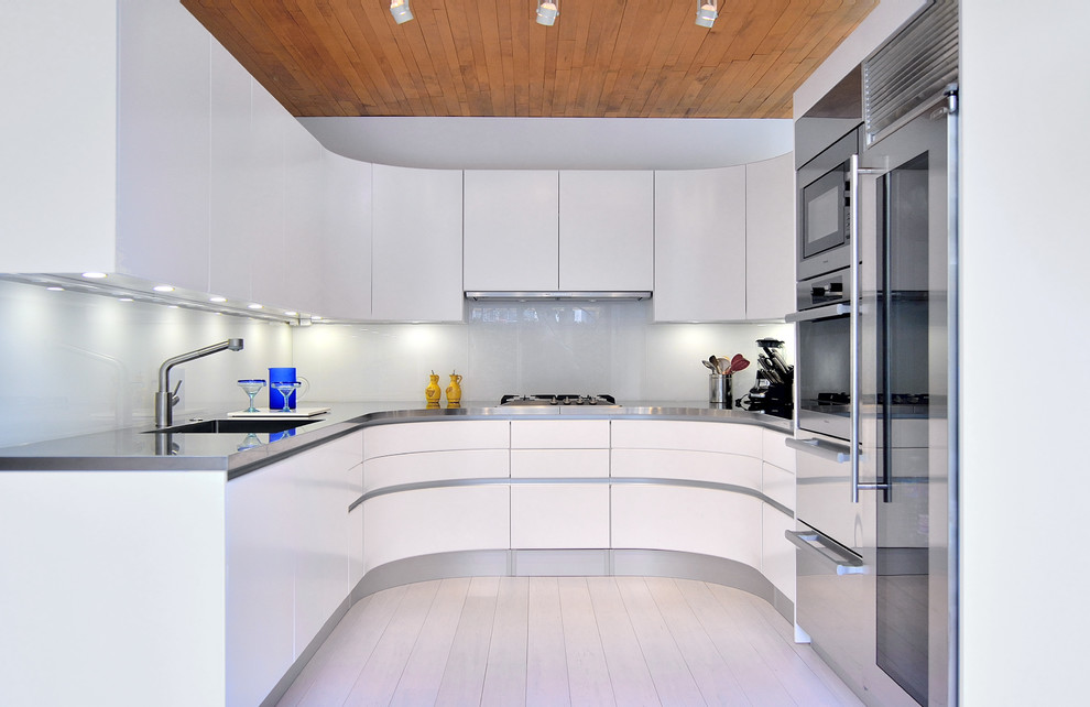 Inspiration for a small contemporary u-shaped enclosed kitchen in DC Metro with an integrated sink, flat-panel cabinets, white cabinets, stainless steel worktops, glass sheet splashback, stainless steel appliances, bamboo flooring and white splashback.