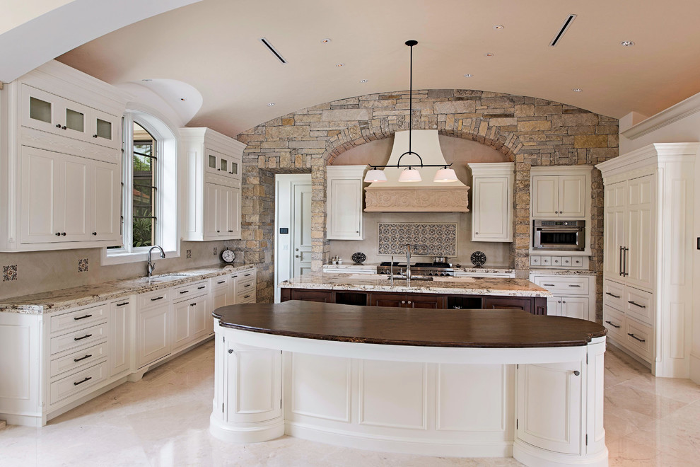 Example of a huge tuscan limestone floor open concept kitchen design in Miami with an undermount sink, beaded inset cabinets, white cabinets, granite countertops, multicolored backsplash, ceramic backsplash, paneled appliances and two islands