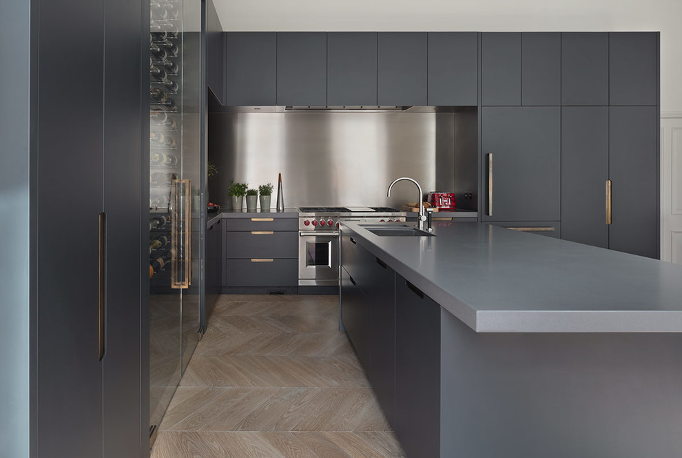 Inspiration for an expansive contemporary galley open plan kitchen in London with a submerged sink, glass-front cabinets, grey cabinets, composite countertops, light hardwood flooring, an island, brown floors and grey worktops.