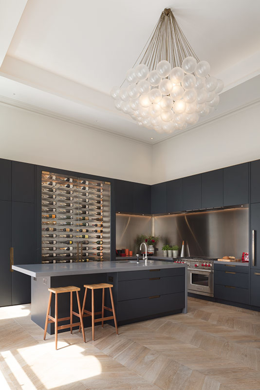 Design ideas for an expansive contemporary galley open plan kitchen in London with a submerged sink, glass-front cabinets, grey cabinets, composite countertops, light hardwood flooring, an island, brown floors and grey worktops.