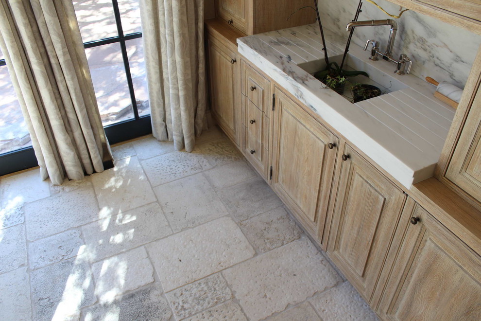 Immagine di una grande cucina mediterranea con ante con bugna sagomata, ante con finitura invecchiata, top in marmo e pavimento in pietra calcarea