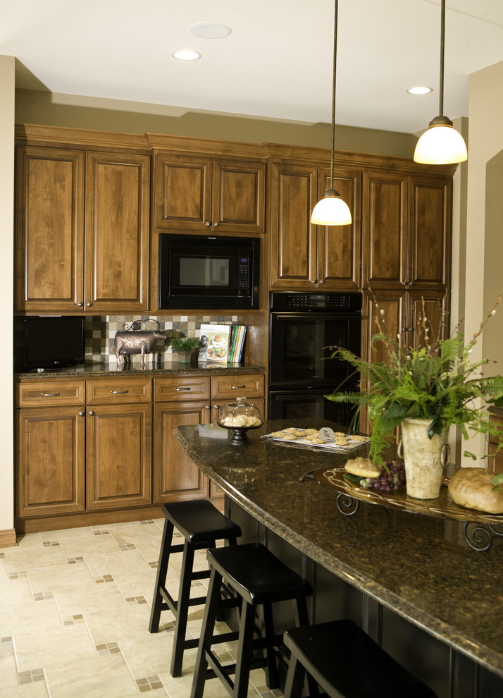 Modelo de cocina tradicional de roble con puertas de armario de madera oscura y electrodomésticos negros