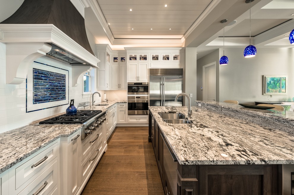 Inspiration for a large coastal u-shaped medium tone wood floor eat-in kitchen remodel in Miami with an undermount sink, shaker cabinets, white cabinets, quartzite countertops, white backsplash, subway tile backsplash, stainless steel appliances and an island