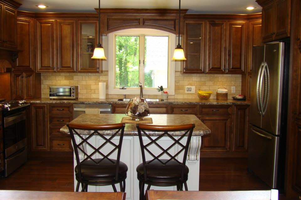 Amerikansk inredning av ett stort kök, med en dubbel diskho, luckor med upphöjd panel, skåp i mörkt trä, granitbänkskiva, beige stänkskydd, stänkskydd i keramik, rostfria vitvaror, mörkt trägolv, en köksö och brunt golv