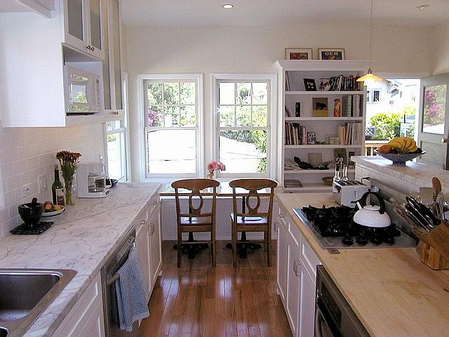 Exempel på ett avskilt, mellanstort klassiskt u-kök, med en dubbel diskho, skåp i shakerstil, vita skåp, marmorbänkskiva, vitt stänkskydd, stänkskydd i tunnelbanekakel, rostfria vitvaror, ljust trägolv och en köksö