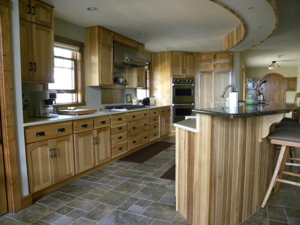 Inredning av ett klassiskt mellanstort kök, med en undermonterad diskho, luckor med upphöjd panel, skåp i mellenmörkt trä, granitbänkskiva, rostfria vitvaror, klinkergolv i keramik, en köksö och grått golv