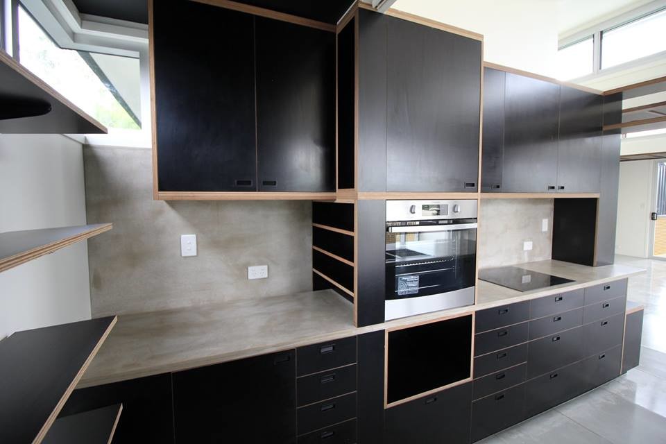 Photo of a medium sized industrial galley open plan kitchen in Other with black cabinets, an island, flat-panel cabinets, concrete worktops, grey splashback, stone slab splashback, stainless steel appliances, concrete flooring and a double-bowl sink.