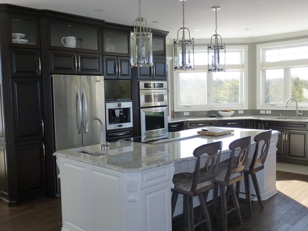 Inspiration for a large traditional l-shaped enclosed kitchen in Toronto with a submerged sink, raised-panel cabinets, dark wood cabinets, engineered stone countertops, grey splashback, matchstick tiled splashback, stainless steel appliances, dark hardwood flooring, an island and brown floors.