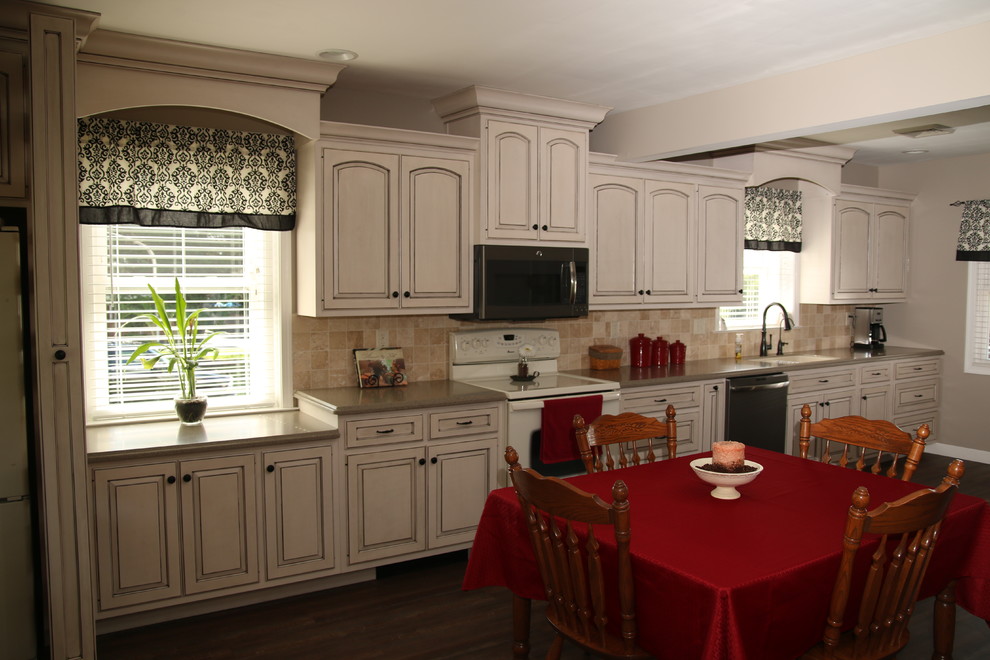 Exempel på ett mellanstort klassiskt linjärt kök och matrum, med en nedsänkt diskho, luckor med upphöjd panel, vita skåp, beige stänkskydd, stänkskydd i stenkakel, vita vitvaror, mörkt trägolv, bänkskiva i kvarts och brunt golv