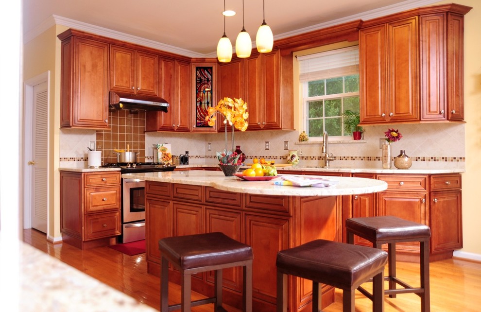 Inredning av ett klassiskt mellanstort kök, med luckor med upphöjd panel, skåp i mörkt trä, granitbänkskiva, beige stänkskydd, stänkskydd i stenkakel, rostfria vitvaror, mellanmörkt trägolv, en köksö och brunt golv