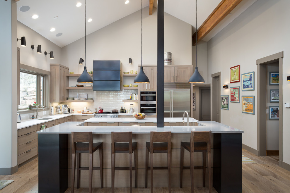 Design ideas for a large classic l-shaped kitchen/diner in Salt Lake City with a submerged sink, shaker cabinets, engineered stone countertops, white splashback, porcelain splashback, stainless steel appliances, multiple islands, light wood cabinets, light hardwood flooring and beige floors.