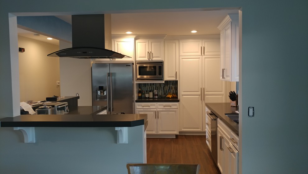 Design ideas for a medium sized classic galley enclosed kitchen in Los Angeles with a submerged sink, raised-panel cabinets, white cabinets, composite countertops, blue splashback, matchstick tiled splashback, stainless steel appliances, dark hardwood flooring, a breakfast bar and brown floors.