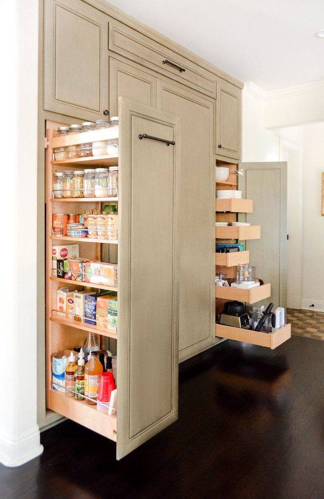 Example of a large tuscan l-shaped dark wood floor and brown floor open concept kitchen design in Los Angeles with an undermount sink, raised-panel cabinets, green cabinets, quartzite countertops, beige backsplash, stone slab backsplash, paneled appliances, an island and beige countertops