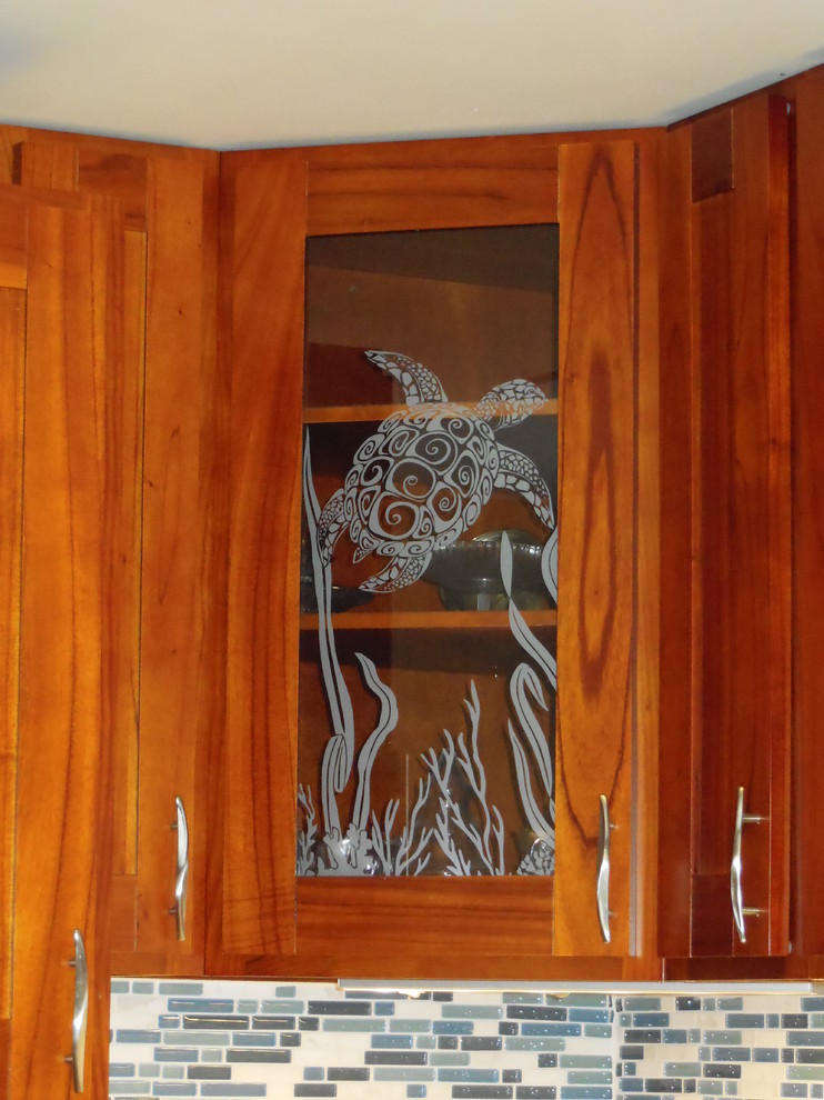 Cette image montre une petite cuisine américaine design en U avec un évier encastré, un placard à porte vitrée, une crédence bleue, une crédence en carreau de verre, un électroménager en acier inoxydable et parquet en bambou.