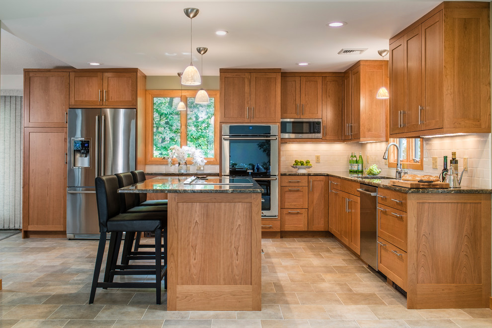 Cette image montre une cuisine design en L et bois brun de taille moyenne avec un plan de travail en granite, un électroménager en acier inoxydable, un sol en carrelage de céramique, îlot et un placard à porte shaker.